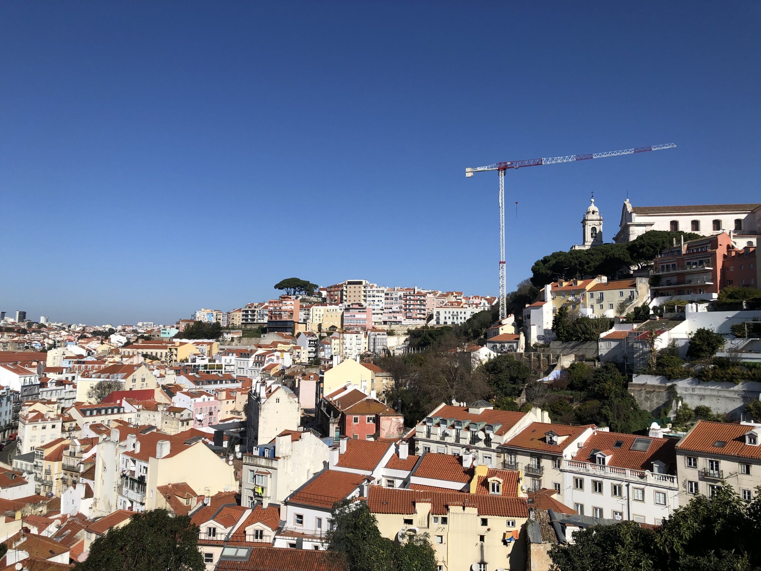A colorful cityscape of Lisbon, Portugal, with houses cascading down a hill overlooking the city.